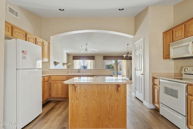 kitchen with a center island, ceiling fan with notable chandelier, white appliances, and light hardwood / wood-style flooring