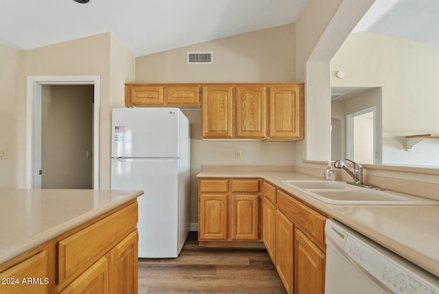 kitchen featuring sink, light brown cabinets, hardwood / wood-style floors, lofted ceiling, and white appliances