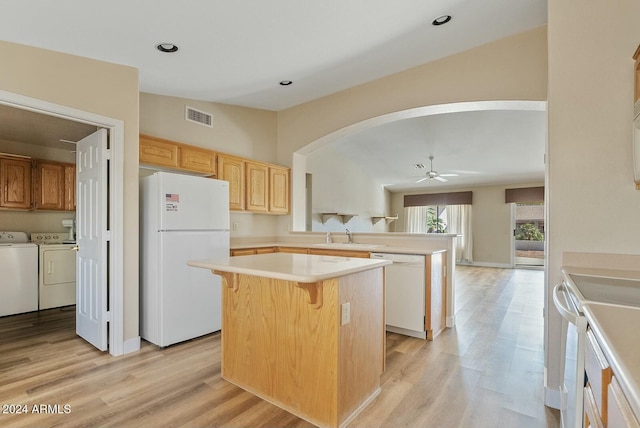 kitchen featuring light hardwood / wood-style floors, a kitchen island, washing machine and dryer, and white appliances