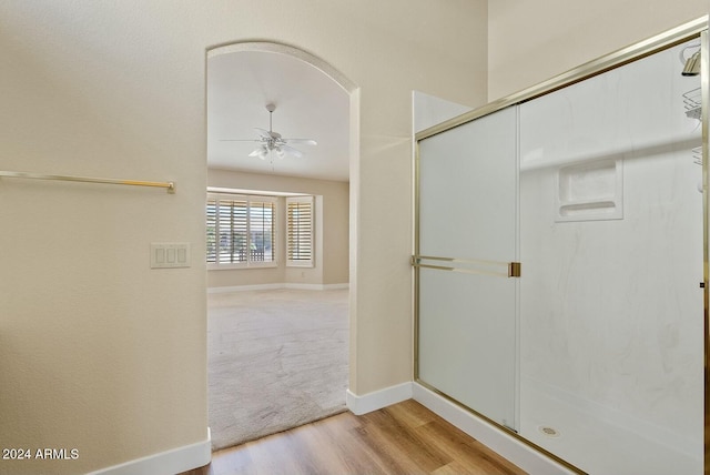 bathroom featuring walk in shower, hardwood / wood-style floors, and ceiling fan