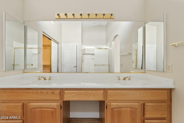 bathroom with vanity, a shower with shower door, and vaulted ceiling