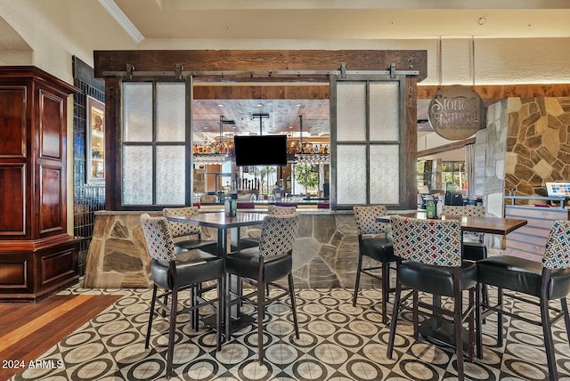 dining space featuring light wood-type flooring, a barn door, and crown molding