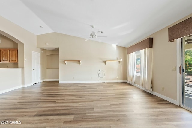 unfurnished living room featuring a healthy amount of sunlight, lofted ceiling, and light hardwood / wood-style floors