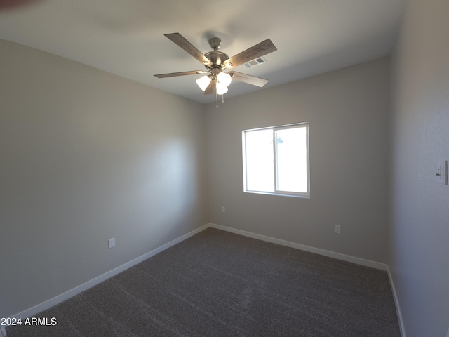 spare room with ceiling fan and dark colored carpet