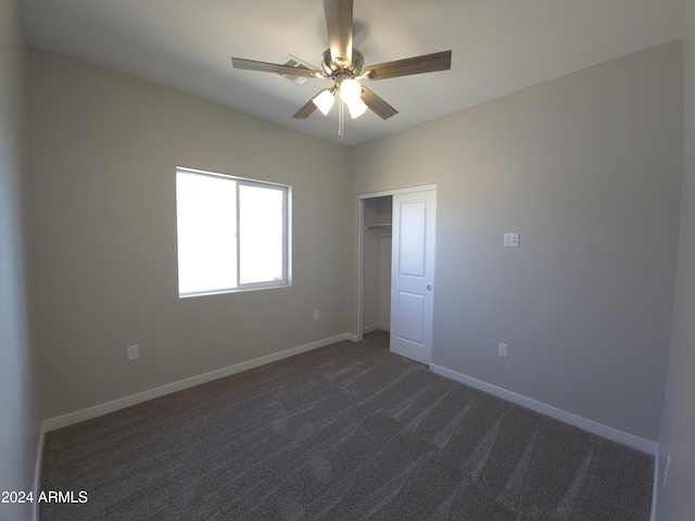 unfurnished room with ceiling fan and dark colored carpet