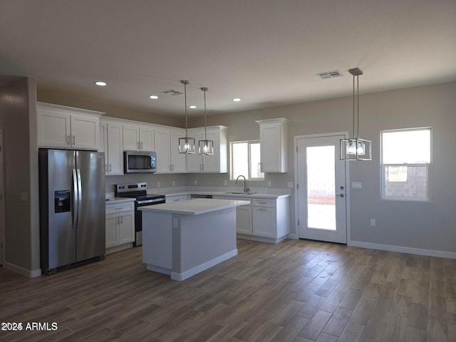 kitchen featuring stainless steel appliances, a center island, hanging light fixtures, and white cabinets