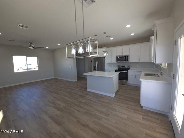 kitchen featuring sink, hanging light fixtures, appliances with stainless steel finishes, a kitchen island, and white cabinets