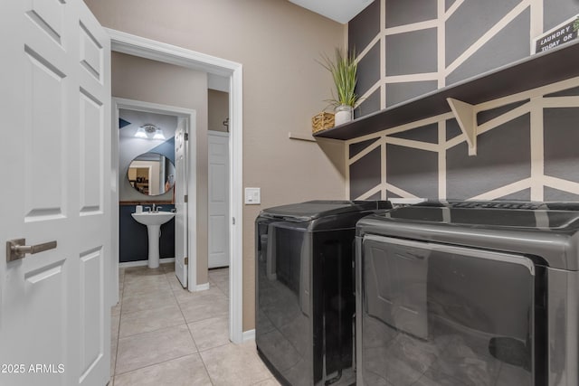 laundry area with independent washer and dryer, light tile patterned floors, and baseboards