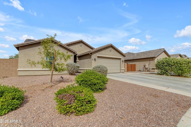 ranch-style home with an attached garage, fence, concrete driveway, and stucco siding