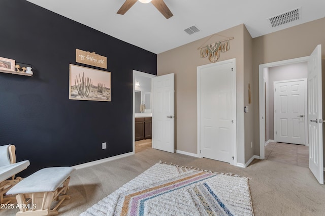 carpeted bedroom with baseboards, connected bathroom, and ceiling fan