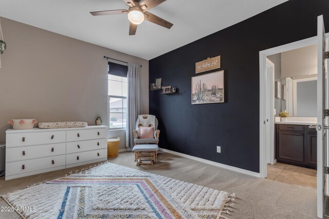 sitting room with ceiling fan, light colored carpet, baseboards, and an accent wall