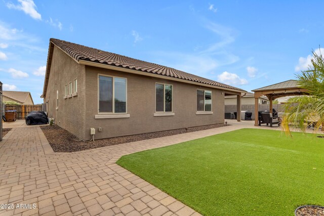 rear view of house featuring a gazebo, a patio, stucco siding, and a tiled roof