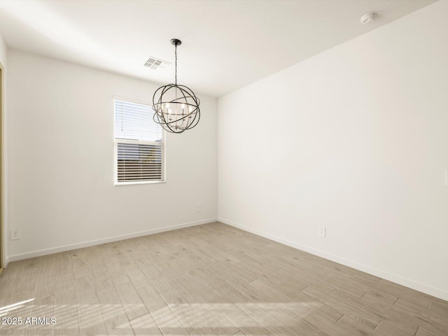 spare room with baseboards, an inviting chandelier, visible vents, and light wood-style flooring