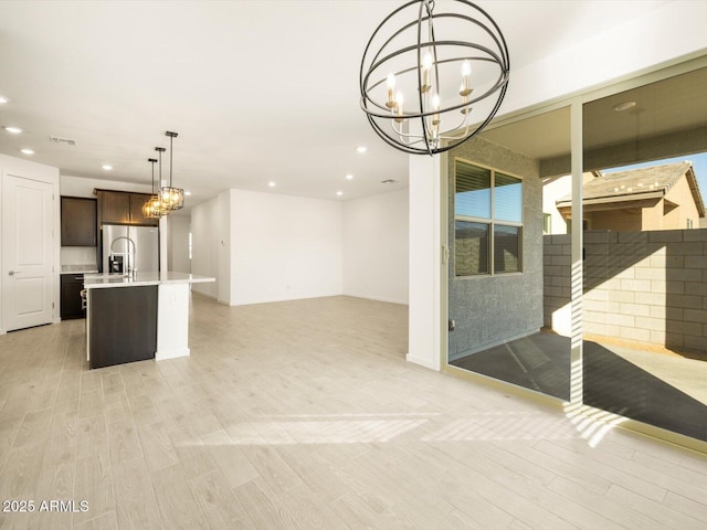 interior space featuring an inviting chandelier, light countertops, dark brown cabinets, and open floor plan