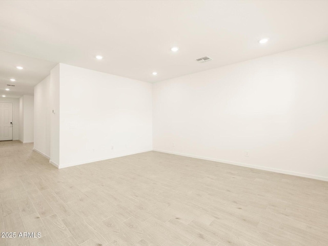 empty room with baseboards, light wood-type flooring, visible vents, and recessed lighting
