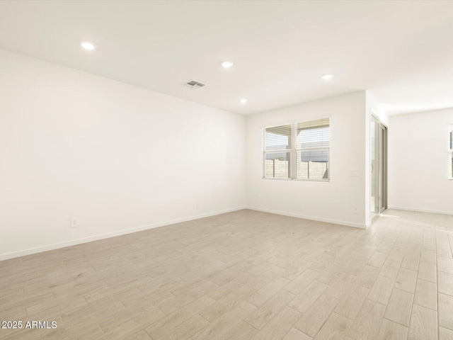 empty room featuring light wood finished floors, visible vents, baseboards, and recessed lighting