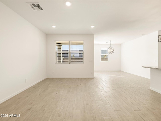 empty room with light wood-style floors, visible vents, baseboards, and recessed lighting