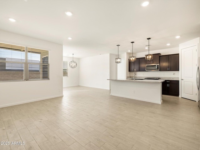 kitchen featuring stainless steel microwave, open floor plan, light countertops, and recessed lighting