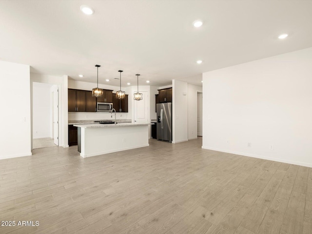 unfurnished living room featuring light wood finished floors, baseboards, a sink, and recessed lighting