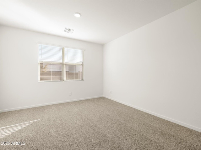 carpeted spare room with visible vents and baseboards