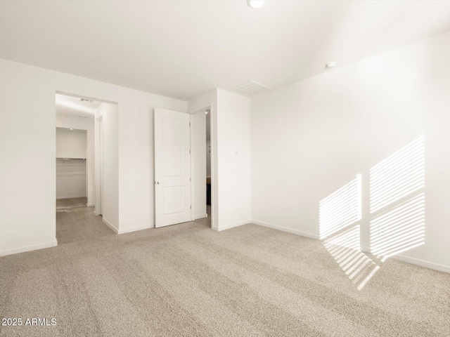 unfurnished bedroom with a spacious closet, carpet floors, baseboards, and a closet
