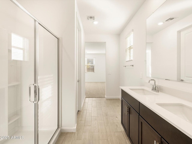 full bathroom featuring a sink, double vanity, a shower stall, and visible vents