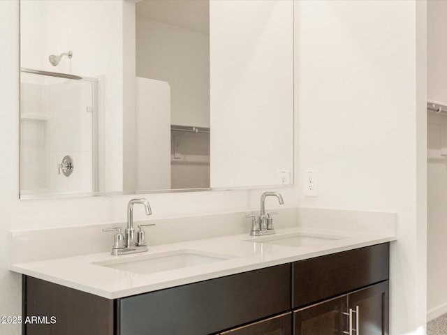 bathroom featuring a shower, double vanity, a sink, and a walk in closet