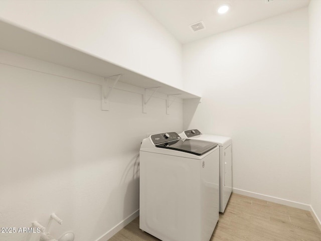 laundry area with light wood finished floors, separate washer and dryer, laundry area, visible vents, and baseboards