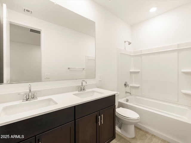 bathroom featuring toilet, bathtub / shower combination, double vanity, and a sink