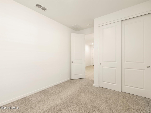 unfurnished bedroom with light colored carpet, baseboards, a closet, and visible vents