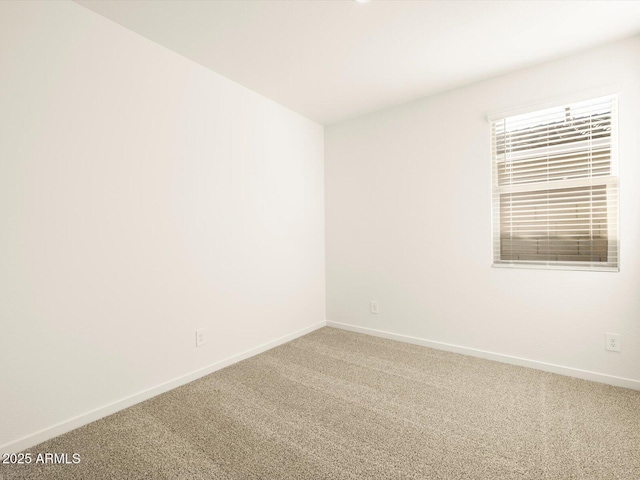 carpeted spare room featuring baseboards
