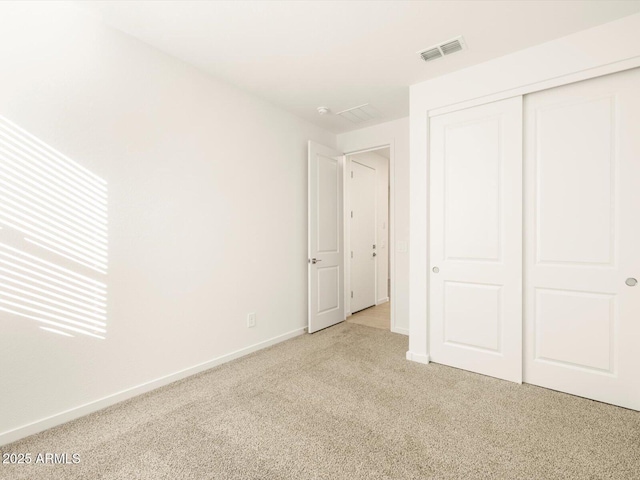 unfurnished bedroom with carpet, baseboards, a closet, and visible vents