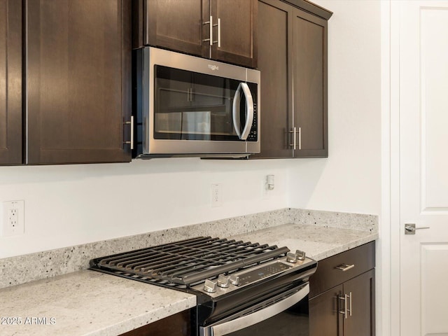 kitchen featuring gas range, light stone counters, stainless steel microwave, and dark brown cabinetry