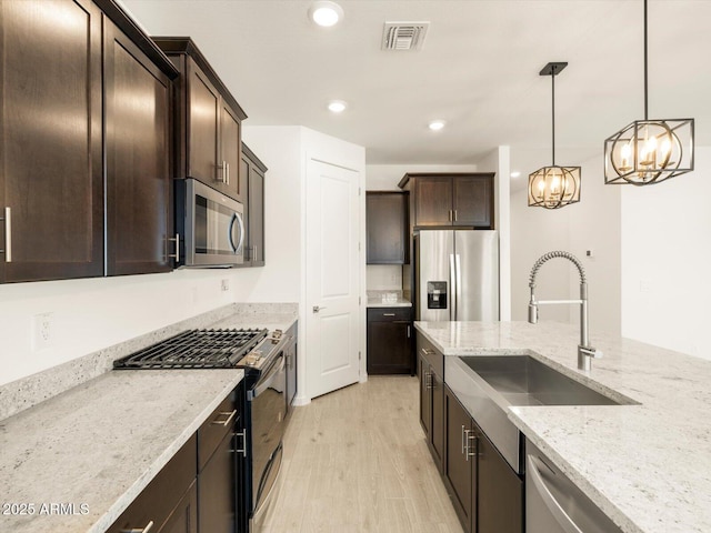 kitchen featuring an inviting chandelier, a sink, dark brown cabinetry, visible vents, and appliances with stainless steel finishes