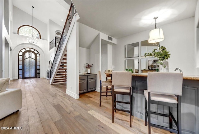 dining area with light wood-type flooring, high vaulted ceiling, and a notable chandelier