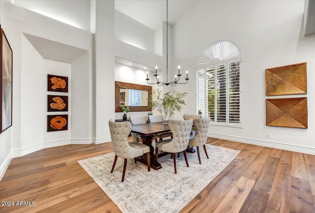 dining space featuring high vaulted ceiling, a notable chandelier, and hardwood / wood-style flooring