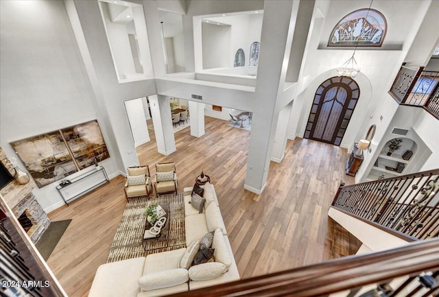 living room with hardwood / wood-style flooring, a fireplace, a high ceiling, and a chandelier