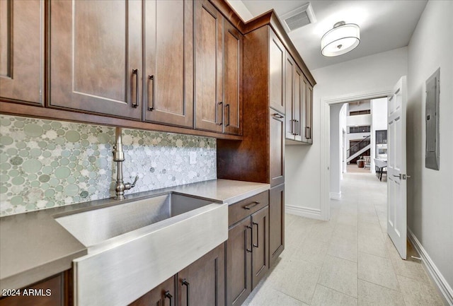 kitchen with electric panel, decorative backsplash, sink, and light tile patterned floors