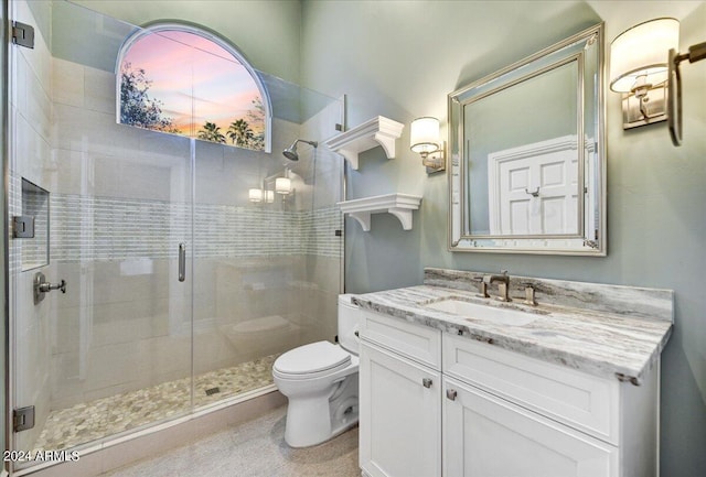 bathroom featuring a shower with door, vanity, and toilet