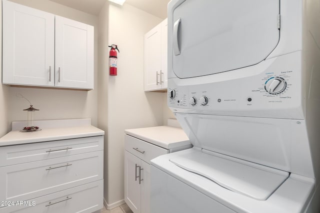 washroom featuring cabinets and stacked washing maching and dryer