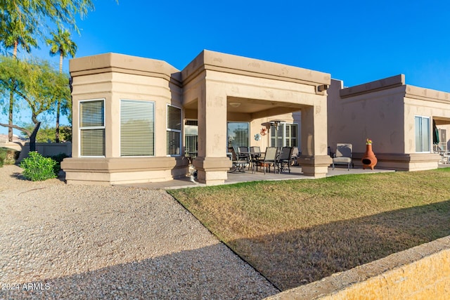 back of property featuring a lawn and a patio