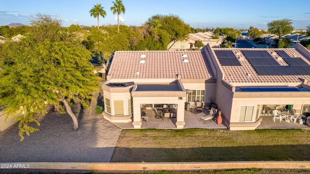 rear view of property with a lawn, solar panels, and a patio area