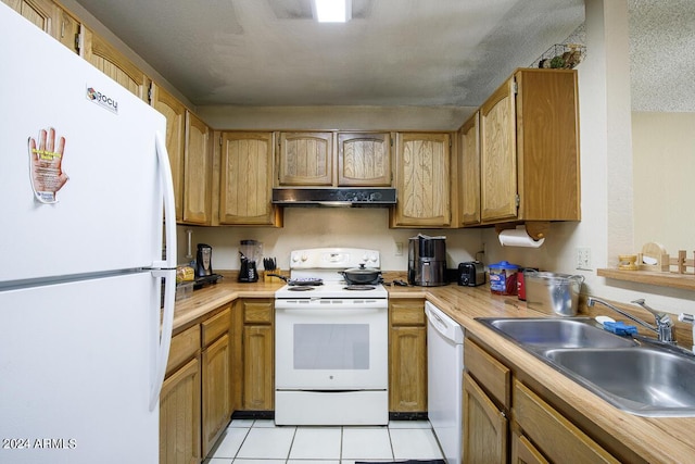 kitchen featuring white appliances, range hood, light tile patterned floors, a sink, and light countertops