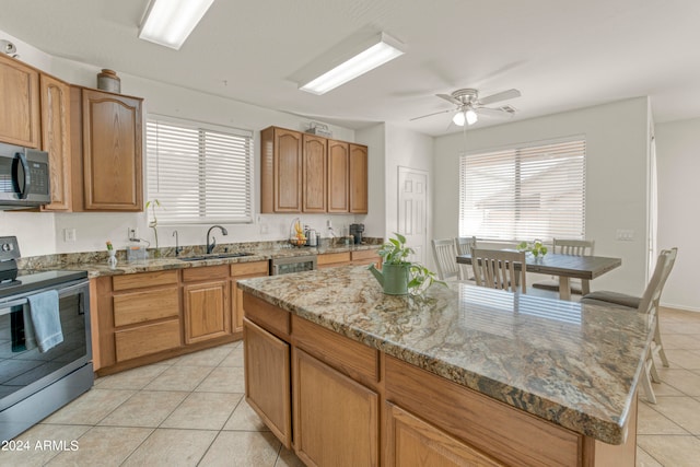 kitchen with a kitchen island, light tile patterned floors, stainless steel appliances, ceiling fan, and sink