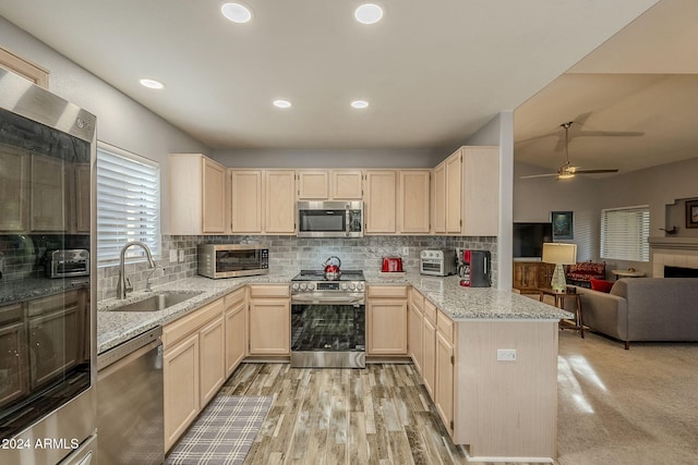 kitchen featuring ceiling fan, sink, stainless steel appliances, kitchen peninsula, and light wood-type flooring