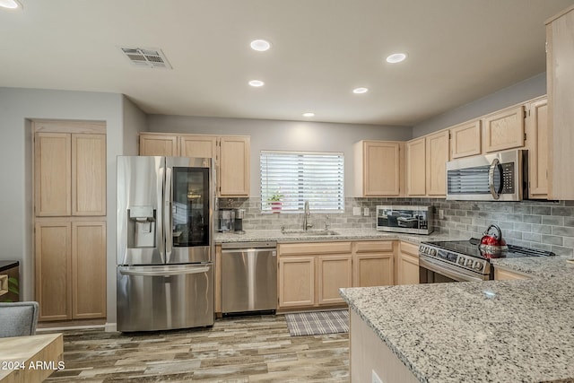 kitchen featuring appliances with stainless steel finishes, light brown cabinets, light hardwood / wood-style floors, and sink