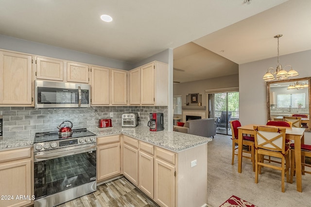 kitchen with an inviting chandelier, appliances with stainless steel finishes, tasteful backsplash, light colored carpet, and a tiled fireplace