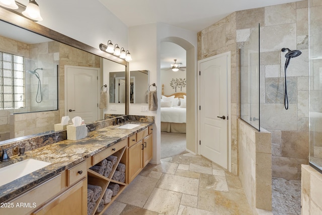 bathroom with a tile shower, vanity, and ceiling fan