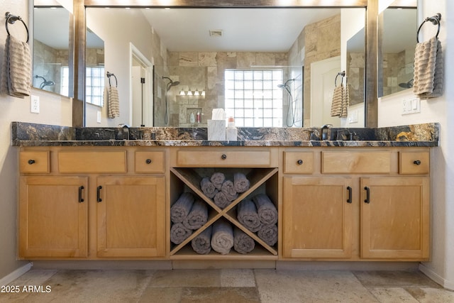 bathroom with a tile shower and vanity