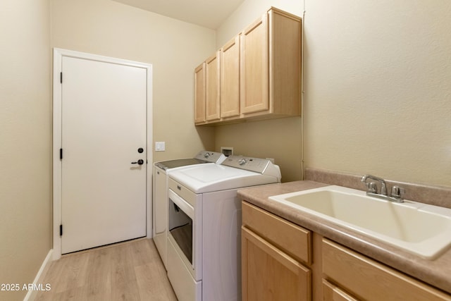 clothes washing area with cabinets, sink, light hardwood / wood-style floors, and independent washer and dryer